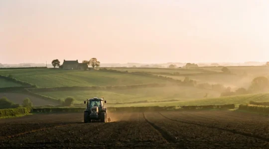 Champ agricole breton au lever du jour avec un tracteur moderne équipé de capteurs de precision, symbolisant l'innovation technologique agricole